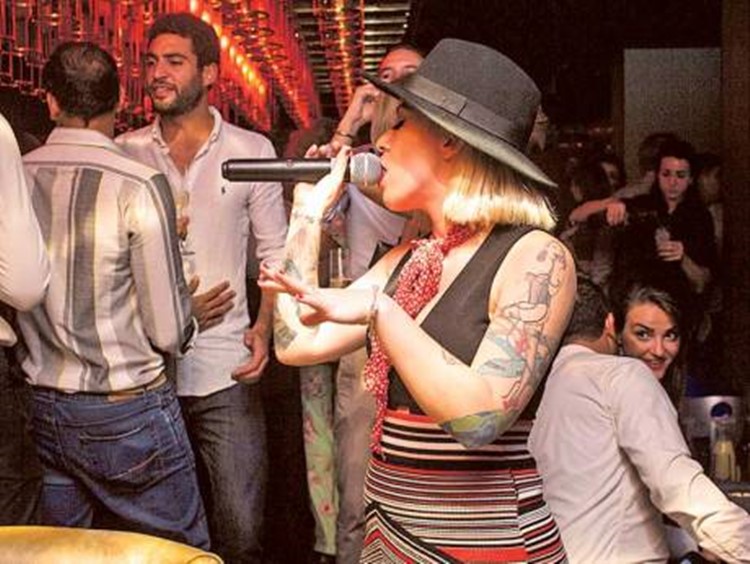 Blonde girl with hat and tattoos singing Kareoke
