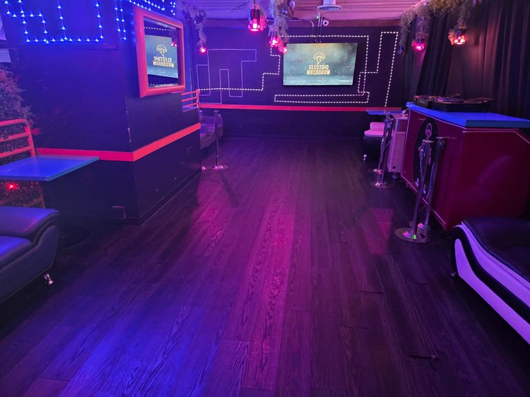 Secondary lounge room at Electric Mushroom with booth seating and red and blue neon strips