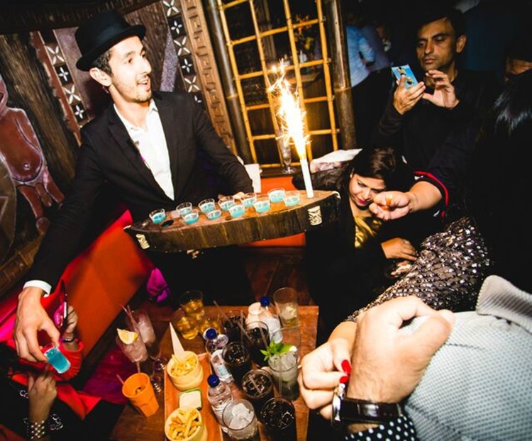 mahiki kensington nightclub london waiter serving alcohol drinks shots to a table booking group of women and men celebrating and having fun