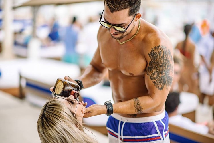 Mandala Beach club Cancun handsome muscular guy pouring alcohol bottle vodka in blonde girl mouth drinks