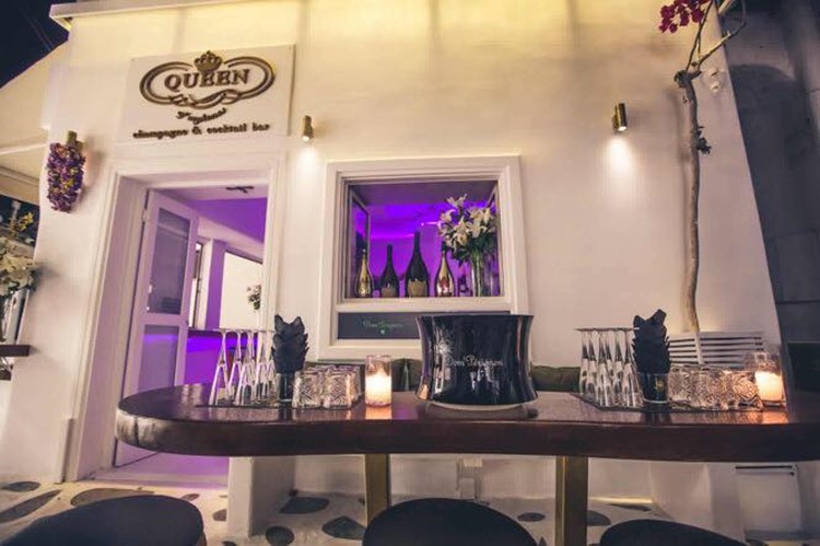 Queen of Mykonos nightclub view of the exterior of the club purple lights inside table full of glasses and alcohol
