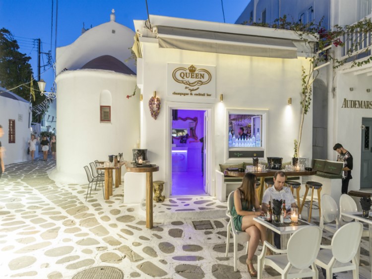 Queen of Mykonos nightclub view of the club's exterior a couple sitting at a table having drinks