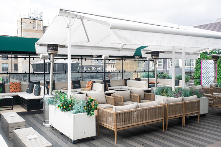 Soho Sky Terrace seen from above with a white awning, planters with citrus trees and patio heaters